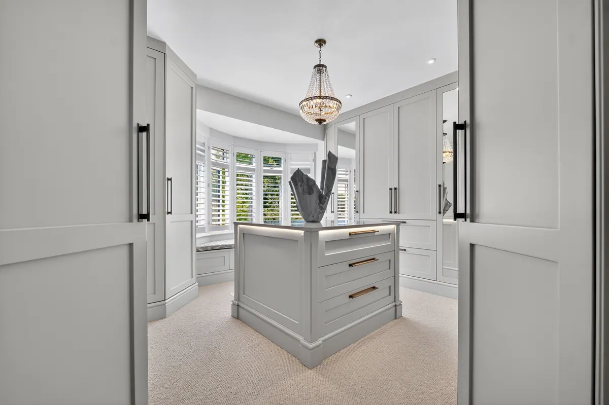 A fitted dressing room with central island by Charles Vivian